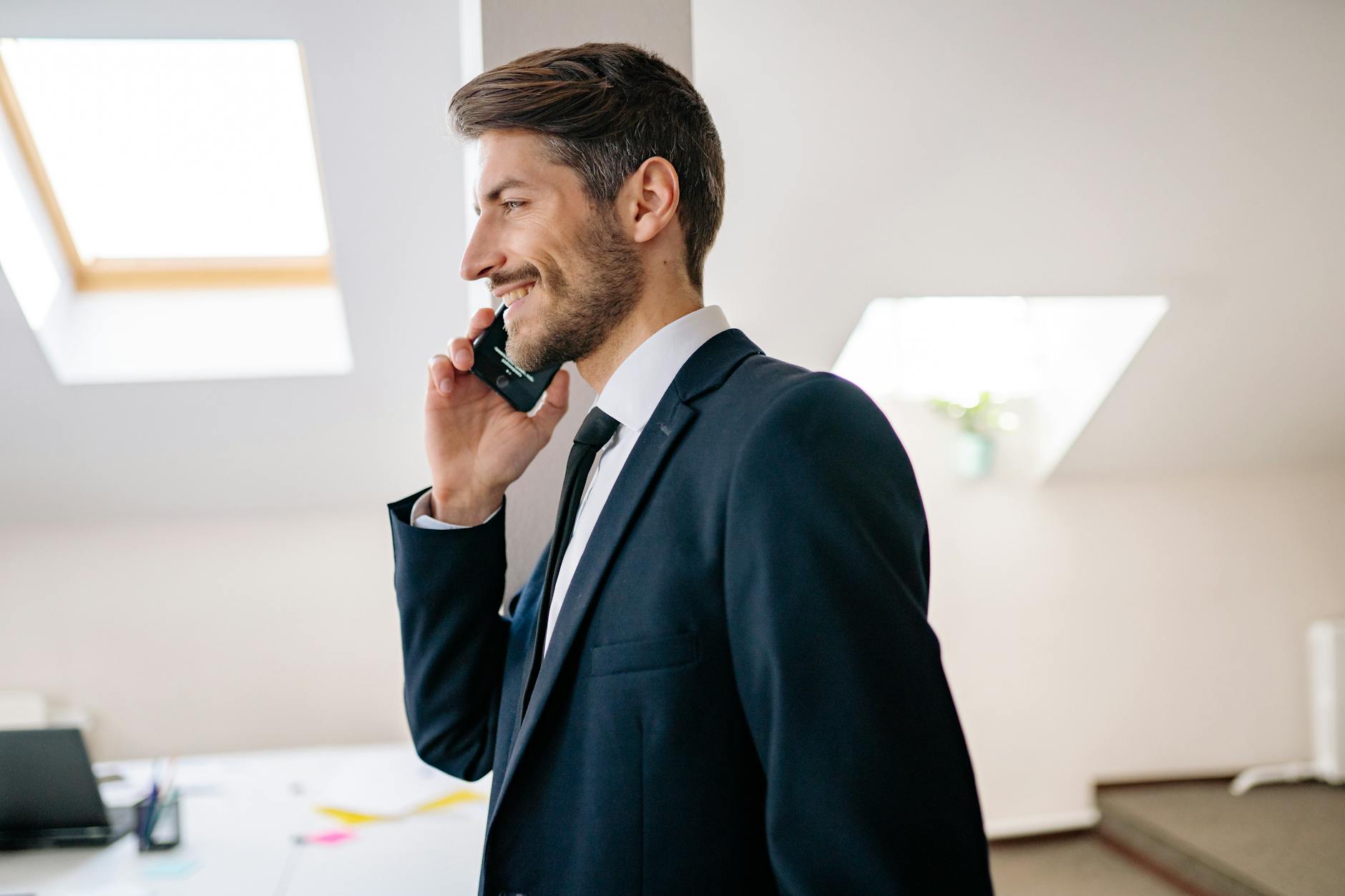 Biznesmen w garniturze rozmawia przez telefon w nowoczesnym biurze