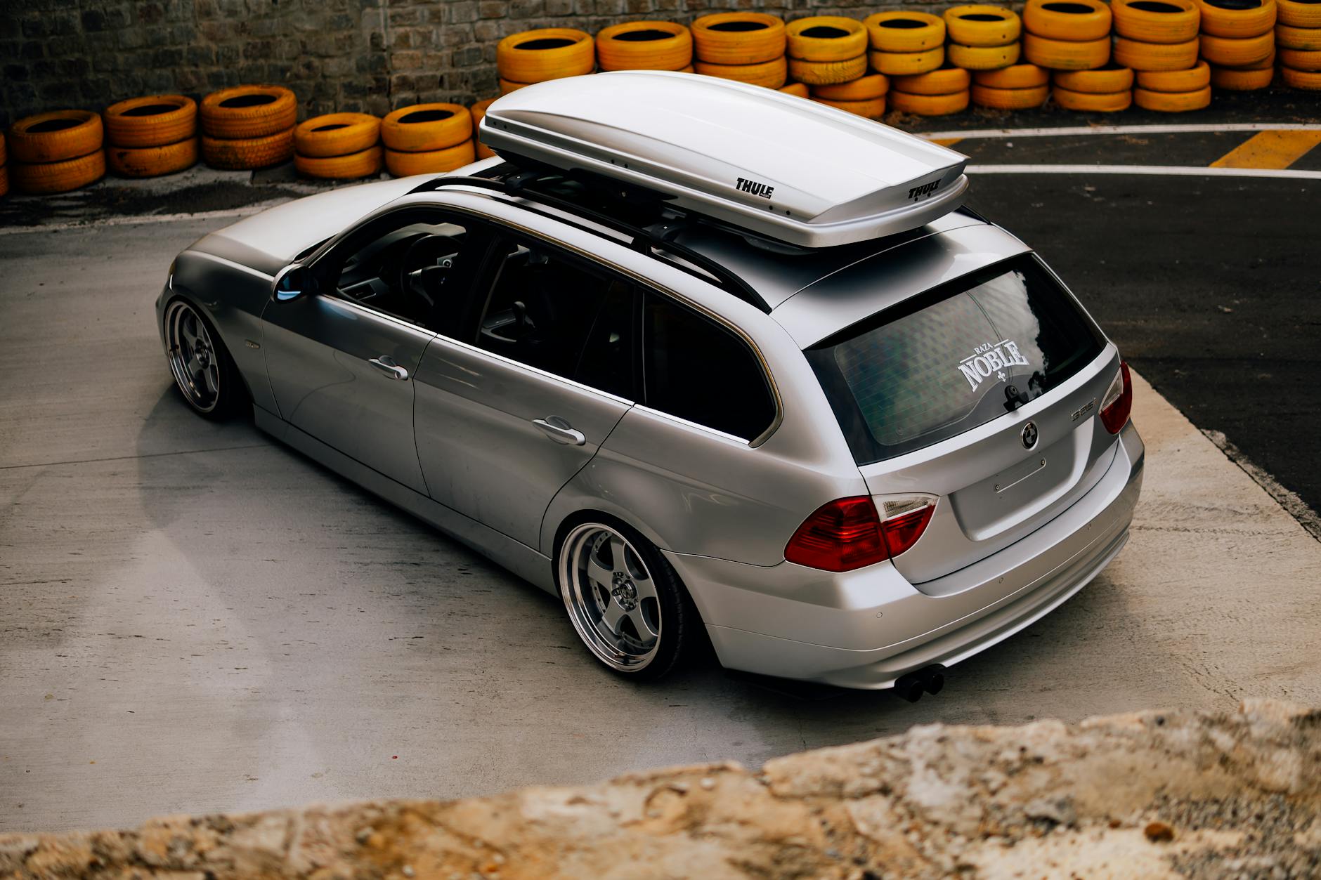 Srebrne kombi BMW z boxem dachowym i obniżonym zawieszeniem na zlocie