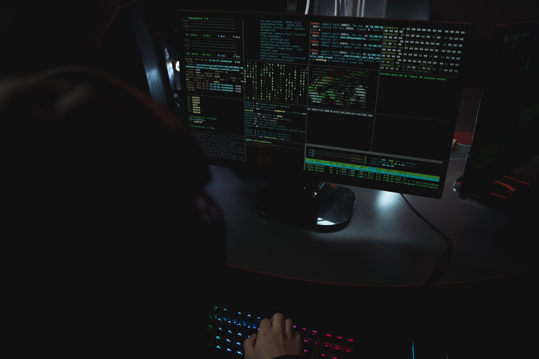 Monitory z kodem w ciemnym pomieszczeniu, motyw cyberbezpieczeństwa