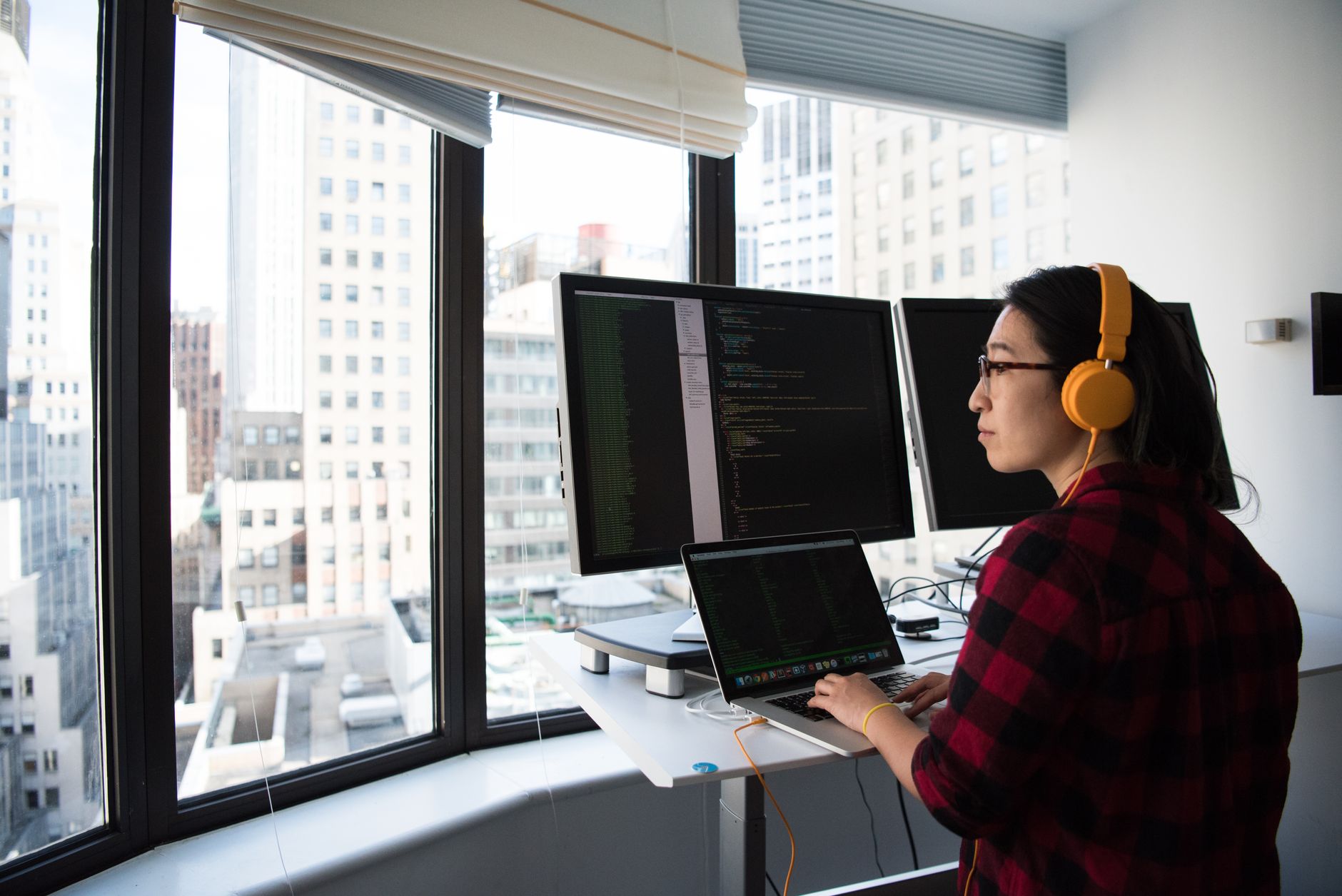 Programistka DevOps przy stojącym biurku koduje aplikację IoT w biurze